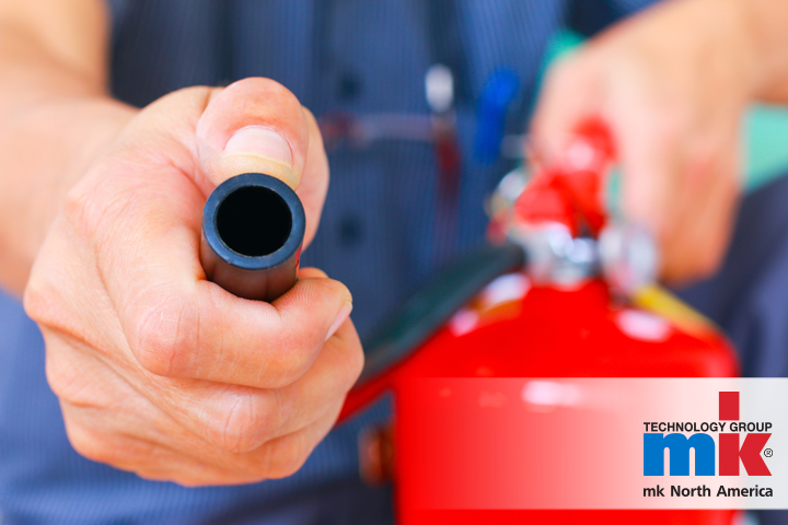 A close up photo of a fire extinguisher being wielded by a man.