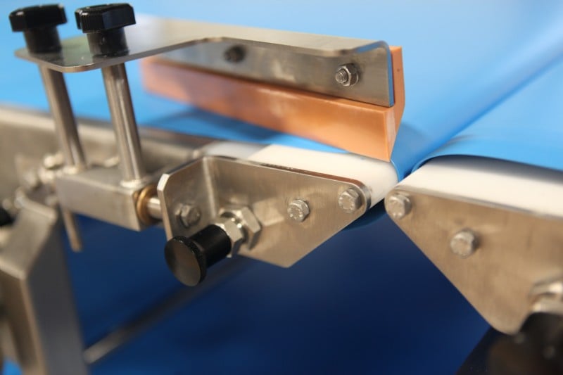 Orange belt scraper on a blue belt stainless steel conveyor