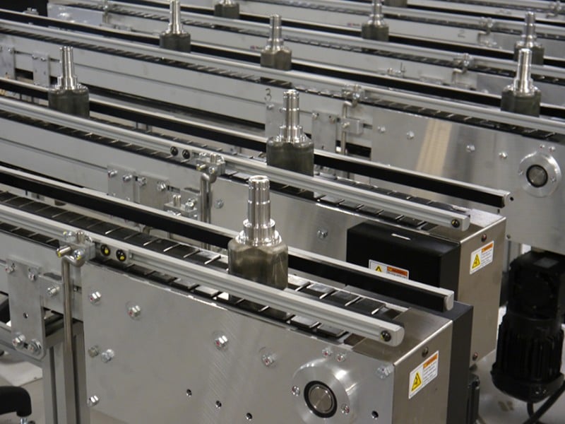 Multiple table top chain conveyors carrying parts