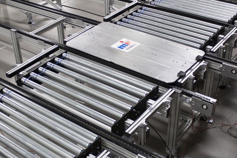 Pallet on a roller conveyor transfering to a chain conveyor