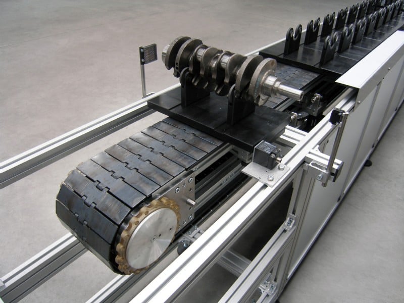 Over under conveyor carrying crank shafts on a pallet