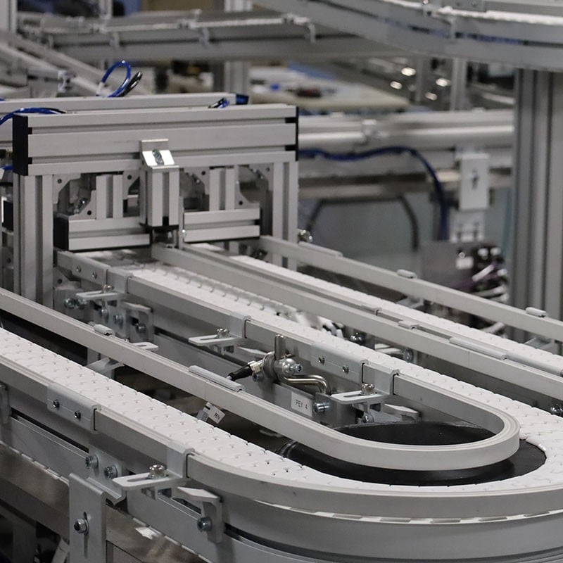 Multiple levels of VersaFlex flat top chain conveyors with curves and a stop gate