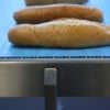 Bread conveyed on a stainless steel blue belt conveyor.