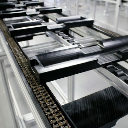 A mk roller chain conveyor featuring attachment chain with plastic pallets bolted to the conveyor chain
